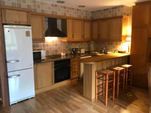 a kitchen with wooden cabinets and a white refrigerator at Apartament de Luxe a Port del Comte in La Coma i la Pedra