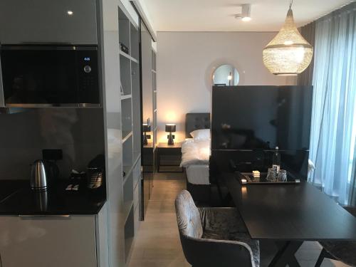 ein Wohnzimmer mit einem schwarzen Tisch und ein Schlafzimmer in der Unterkunft Sky Aparthotel in Stuttgart