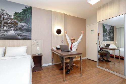 a woman sitting at a desk with her arms in the air at Mercure Sao Paulo Alamedas in Sao Paulo