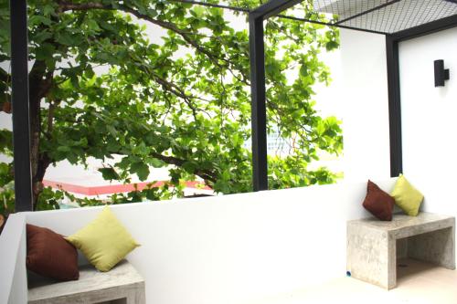a white bench with pillows sitting in front of a window at Jamjuree Home at Udonthani in Udon Thani