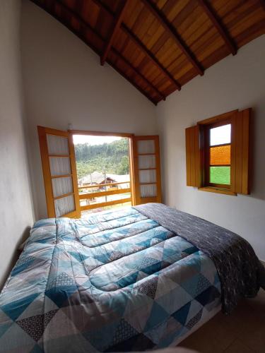 a bedroom with a bed and a large window at Claire Cottage in Monte Verde