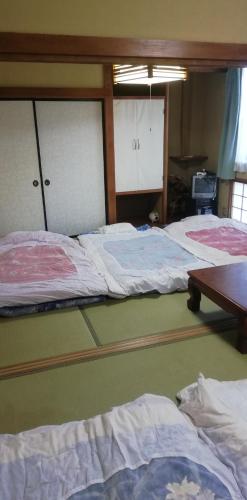 a room with three beds and a wooden table at Suijin Hotel - Vacation STAY 38314v in Chichibu