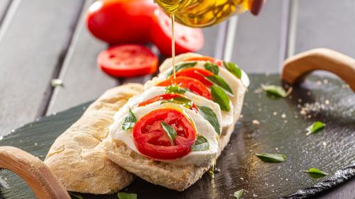 a sandwich with tomatoes and cheese on a table at Kembali Hotel Porto de Galinhas - Adults Only in Porto De Galinhas