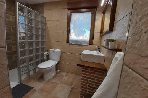 baño con aseo y lavabo y ventana en La Morada de los Olmos, en Segovia