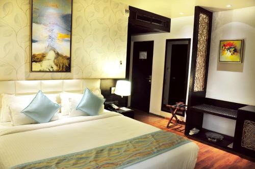 a bedroom with a large white bed with blue pillows at Hotel Senses in Kolkata