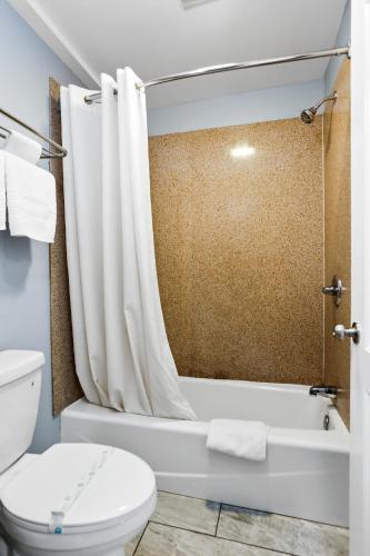 a bathroom with a toilet and a bath tub with a shower curtain at 3rd Avenue Inn in La Habra