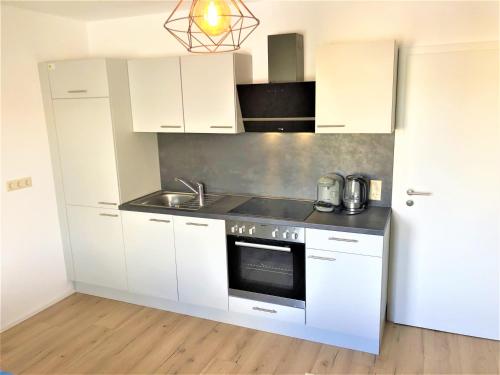 a white kitchen with a sink and a stove at 3Rooms Central-Modern- The Alps by SA-Grandeur in Friedrichshafen