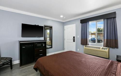 a bedroom with a bed and a flat screen tv at 3rd Avenue Inn in La Habra