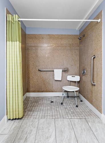 a bathroom with a yellow shower curtain and a stool at 3rd Avenue Inn in La Habra