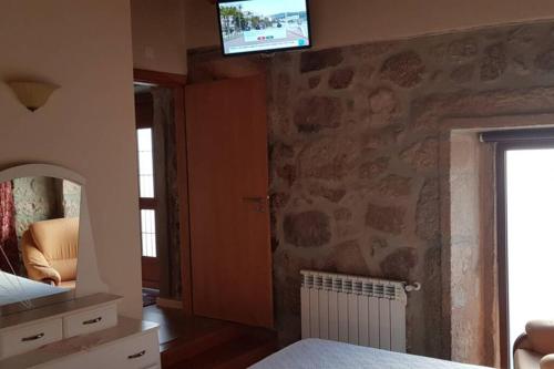 a bedroom with a tv on a stone wall at Casa Bento Moura Portugal in Moimenta da Serra