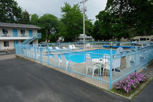 ein blauer Zaun um einen Pool mit weißen Stühlen in der Unterkunft Starlite Motel in Wisconsin Dells