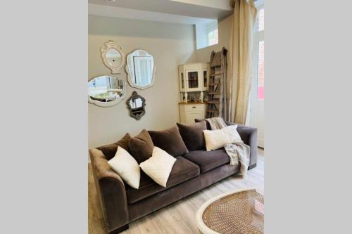 a living room with a brown couch and mirrors at Cosy house in a charming village in Beauvechain