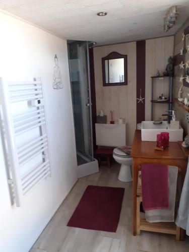 La salle de bains est pourvue d'un lavabo, de toilettes et d'une table. dans l'établissement Belle de nuit, à Le Trait dʼUnion