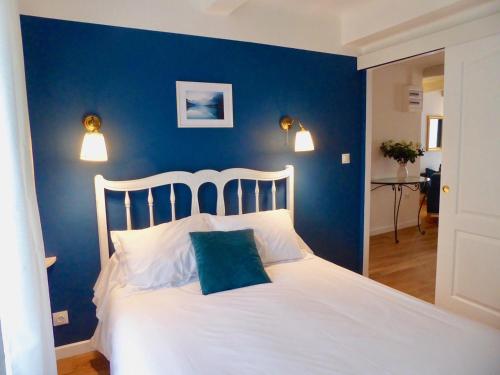 a bedroom with a white bed with a blue wall at La Lavandière in Puimoisson