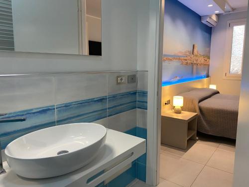 a bathroom with a white sink and a bedroom at 103 Boutique Hotel Stintino in Stintino