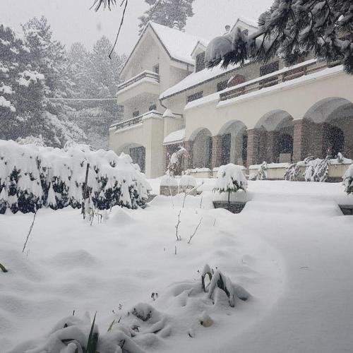 a snow covered yard in front of a building at Hotel Alpin Llogara in Llogara
