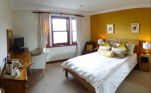 a bedroom with a bed and a desk and a window at Ardno House B & B in Glencoe