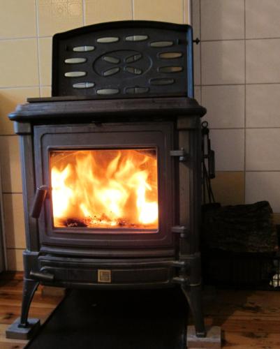 a stove with a fire inside of it at Domek Drewniany in Nowa Wola
