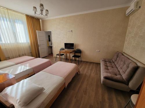 スラヴャンスク・ナ・クバニにあるMini-Hotel Svetlanaのベッド2台とソファが備わるホテルルームです。