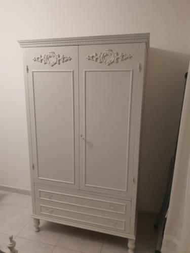 un armario blanco con dos puertas junto a una pared en LA CASA DI NONNA LUCIA en Torre Canne