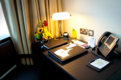 a desk in a hotel room with a telephone and flowers at Cristal Hotel Abu Dhabi in Abu Dhabi