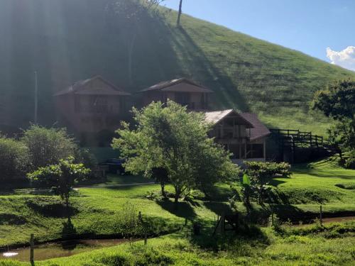 a house on the side of a green hill at POUSADA BELA HELENA in Visconde De Maua
