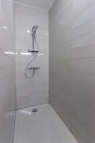 une douche avec pommeau de douche dans une salle de bain dans l'établissement Le 04-GregIMMO-Appart'Hôtel, à Montbéliard