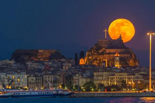 a full moon rising over a city with a cruise ship at Amalia Complex in Nisakion