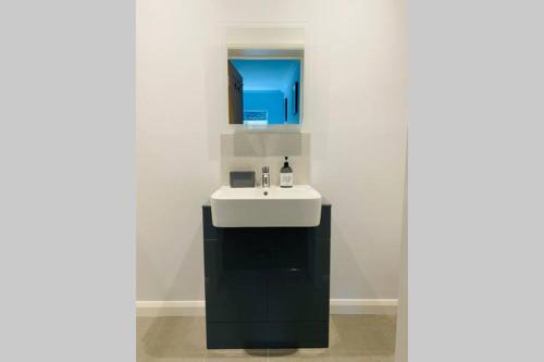La salle de bains est pourvue d'un lavabo blanc et d'un miroir. dans l'établissement Luxury Apartment-Golden Triangle, Parking & Garden, à Norwich