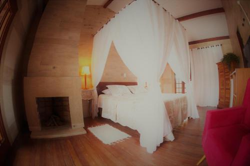 a bedroom with a white bed and a fireplace at Hotel Ferrugem Eco Village in Garopaba