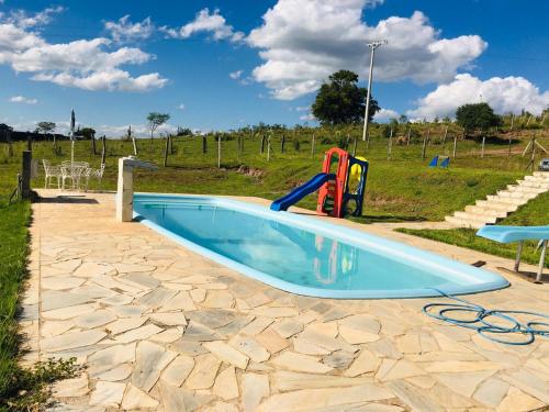 a swimming pool with a slide and a playground at Sítio Santo Agostinho in Porangaba
