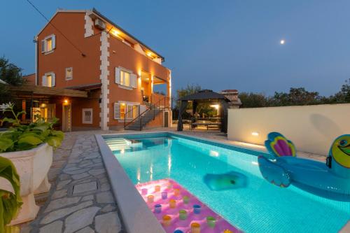 a swimming pool in a backyard with a house at Villa Spark with heated pool in Rogoznica Zecevo in Zečevo Rogozničko