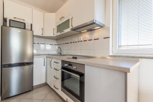 a kitchen with a stainless steel refrigerator and white cabinets at Villa Spark with heated pool in Rogoznica Zecevo in Zečevo Rogozničko