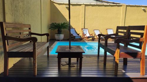 eine Terrasse mit einem Tisch und Stühlen sowie einem Pool in der Unterkunft Pousada Búzios Garden in Búzios