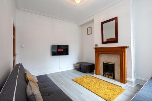 a living room with a couch and a fireplace at 4 Bedroom House-City Centre- Free Parking-Sleeps 9 in Stoke on Trent