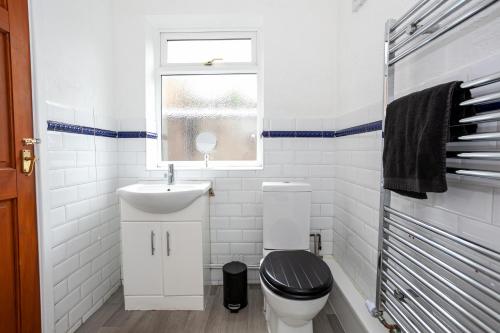 a bathroom with a toilet and a sink and a window at Stay Comfortable-City Centre Location- Sleeps up to 9 in Stoke on Trent