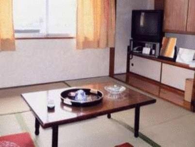 a living room with a coffee table and a tv at Tenryu Ryokan in Hiroshima