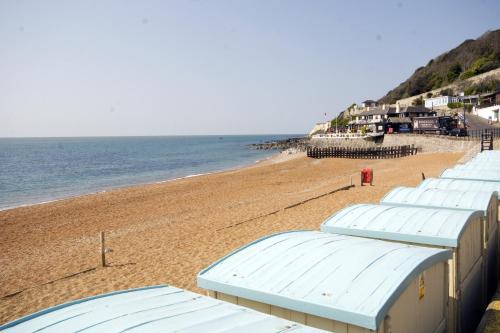a beach with a bunch of white buildings and the ocean at Enjoy Ventnor 1, Pier Street, Wightlink offer in Ventnor