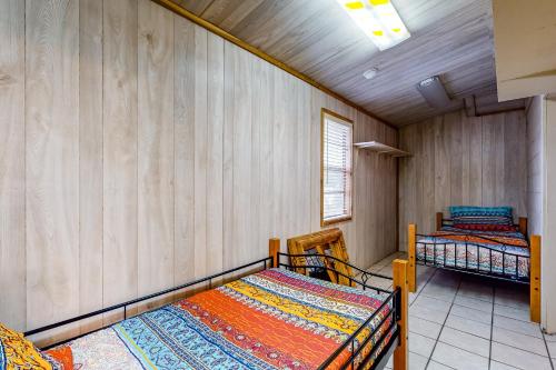two beds in a room with wooden walls at Green Harbor Lake House in Kingsland