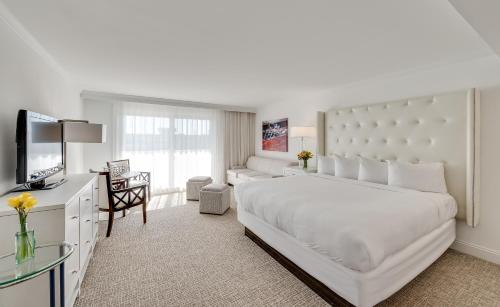 a white bedroom with a large bed and a television at ICONA Avalon in Avalon