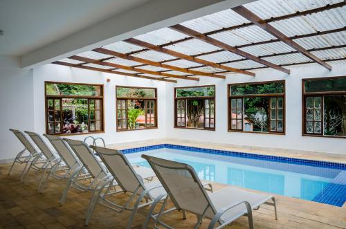 a swimming pool with chairs and a table in a house at Pousada Quinta da Jade in Itaipava