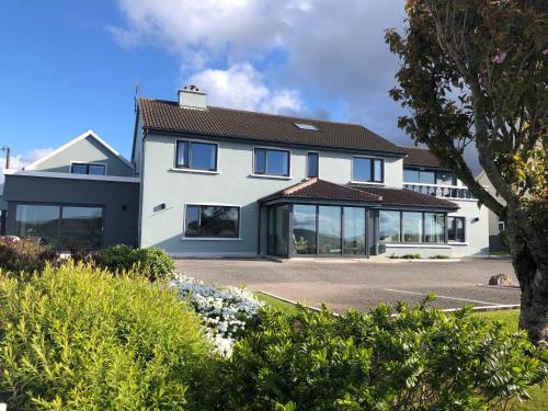 Cette grande maison blanche possède de nombreuses fenêtres. dans l'établissement Cill Bhreac House B&B, à Dingle