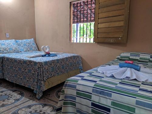 a bedroom with two beds and a window at Chalé Cantinho Meu in Barreirinhas