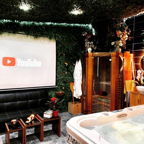 uma apresentação com um ecrã e uma banheira numa sala em Jungle Vibes - Jacuzzi - Sauna em Yerres