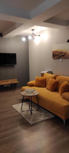 uma sala de estar com um sofá amarelo e uma mesa em Apartament 31 Kozubnik joy&love em Porąbka