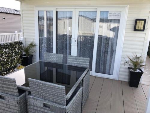 a screened in porch with a glass door at Beautiful Spacious Holiday Home - Romney Sands in New Romney