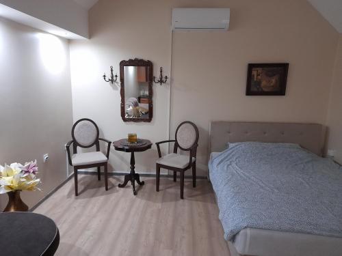 a bedroom with a bed and two chairs and a table at Wanted Šabac apartman in Šabac