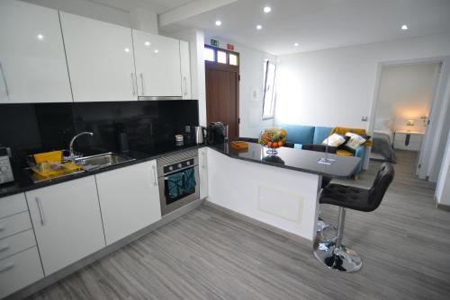 a kitchen with white cabinets and a bar stool at Casas do Baleeiro - Whaler's Houses in Caniçal