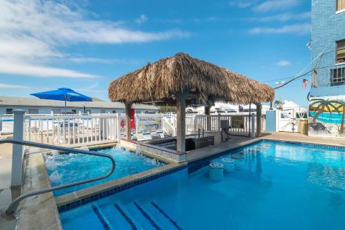 una piscina con sombrilla de paja y un complejo en Oceanic Hotel & Barefoot Tiki Bar, en Wildwood