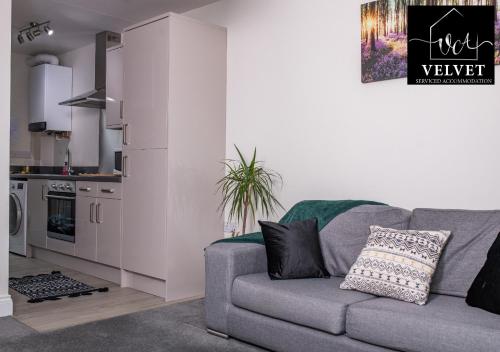 a living room with a gray couch and a kitchen at 1 Bed House , Free WiFi,Free Parking,Leasure,Business in Swansea